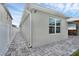 Side exterior view featuring the property's neutral paint, window, hardscape pathway, and open lanai at 2838 Common Crane Ct, Harmony, FL 34773
