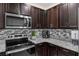 This modern kitchen has granite countertops, stainless steel appliances, and dark wood cabinetry at 2838 Common Crane Ct, Harmony, FL 34773
