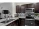Well-equipped kitchen with stainless steel appliances, granite countertops, tiled backsplash, and dark wood cabinets at 2838 Common Crane Ct, Harmony, FL 34773