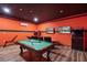 Orange game room featuring a pool table, arcade games, and two wall mounted televisions at 331 Pendant Ct, Kissimmee, FL 34747