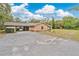 Spacious driveway leads to a home featuring a brick facade and an American flag, set amidst lush greenery and a carport at 4410 Mildred Bass Rd, St Cloud, FL 34772