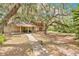 Exterior shot of house with two-car garage, lawn tractor, large tree with Spanish moss and walkway at 4410 Mildred Bass Rd, St Cloud, FL 34772