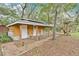 Charming wooden cabin with a front porch and rocking chair nestled among mature trees in the backyard at 4410 Mildred Bass Rd, St Cloud, FL 34772