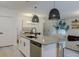 Open-concept kitchen with island, stainless steel appliances, pendant lights, and seamless flow into the living and dining areas at 466 Cool Summer Ln, Davenport, FL 33837