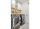 Laundry room with front-load washer and dryer, white cabinets, open shelves, and modern design at 466 Cool Summer Ln, Davenport, FL 33837