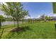 Large grassy backyard surrounded by a black aluminum fence, with a pond view at 5648 Cedar Chase Dr, St Cloud, FL 34771