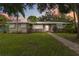 Charming single-story home featuring a metal roof, lush landscaping, and a welcoming walkway at 612 Lakeshore Blvd, Kissimmee, FL 34744
