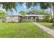Charming single-story home featuring a metal roof, lush landscaping, and a welcoming walkway at 612 Lakeshore Blvd, Kissimmee, FL 34744