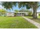 Charming single-story home boasts lush lawn, mature trees, and inviting walkway to the front door at 612 Lakeshore Blvd, Kissimmee, FL 34744