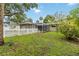 A view of the home's backyard with screened in lanai, well maintained lawn, and picket fence at 612 Lakeshore Blvd, Kissimmee, FL 34744