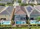 Aerial view of house showing tile roof, solar panels, screened pool and hot tub with manicured backyard at 7613 Brookhurst Ln, Kissimmee, FL 34747