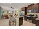 Open kitchen with stainless steel appliances, granite countertops, island with barstool seating, and dark wood cabinetry at 7613 Brookhurst Ln, Kissimmee, FL 34747
