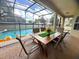 Charming outdoor dining area with a view of the screened-in pool, creating a perfect space for gatherings at 7751 Tosteth St, Kissimmee, FL 34747