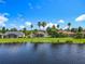 Water view of backyard featuring several screened lanais, a manicured lawn and various mature palm trees at 777 Glendora Road, Poinciana, FL 34759