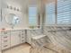 Bright bathroom featuring white cabinets, a modern mirror, and a marble-tiled walk-in shower with bench at 777 Glendora Road, Poinciana, FL 34759