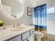 Bathroom with white cabinets, a modern round mirror, and a shower with a blue patterned curtain at 777 Glendora Road, Poinciana, FL 34759