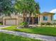 Charming single-story home featuring a well-manicured lawn, mature palm trees, and a brick-paved driveway at 777 Glendora Road, Poinciana, FL 34759