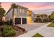 Modern two-story home featuring a two-car garage, stone accents, and a balcony, set against a colorful sunset sky at 7802 Palmilla Ct, Reunion, FL 34747