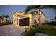 Two-story home with a black garage door, and a brick paver driveway and professional landscaping at 1005 Coyote Creek Way, Reunion, FL 34747