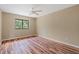 Bright bedroom featuring hardwood floors, a ceiling fan, and a window offering a scenic view at 11323 Kijik Trl, Groveland, FL 34736