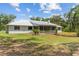 Charming single-story home featuring a metal roof, screened porch, and spacious yard surrounded by trees at 11323 Kijik Trl, Groveland, FL 34736