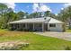 Exterior view of a charming home with a metal roof, screened porch, and mature landscaping at 11323 Kijik Trl, Groveland, FL 34736