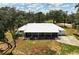Exterior shot of home with white paint, metal roof, circular drive and mature trees at 11323 Kijik Trl, Groveland, FL 34736