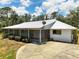 Exterior shot of home with white paint, metal roof, circular drive and screened in porch at 11323 Kijik Trl, Groveland, FL 34736
