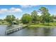 Waterfront view featuring a wooden dock leading out to a calm lake surrounded by green trees and lush landscapes at 1186 Laguna Cir, St Cloud, FL 34771