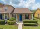 Charming townhome featuring a blue front door, manicured landscaping, and a cozy covered porch at 13636 Beauregard Pl, Orlando, FL 32837