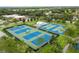 Aerial view of well-maintained tennis courts, basketball court and surrounding green spaces with walking path at 13636 Beauregard Pl, Orlando, FL 32837