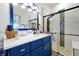 Modern bathroom featuring a blue vanity and an adjacent glass enclosed shower with tiled walls at 168 Club Villas Ln, Kissimmee, FL 34744