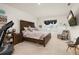 Cozy bedroom with a wooden headboard bed frame, a wall-mounted TV, and a comfortable armchair at 176 Sofia Ln, Lake Alfred, FL 33850