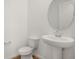 Powder bath featuring a pedestal sink, round mirror, and wood-look flooring at 208 Flag Lilly Ln, Umatilla, FL 32784