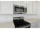 Close-up of stainless steel microwave and stove top over white quartz counters at 208 Flag Lilly Ln, Umatilla, FL 32784