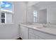 Bright bathroom with double sinks, white cabinets, and a large mirror reflecting a window at 212 Flag Lilly Ln, Umatilla, FL 32784