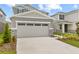 Two car garage of a gray two story home with stone veneer and manicured lawn at 212 Flag Lilly Ln, Umatilla, FL 32784