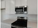 Close up on stainless steel microwave and oven in bright kitchen with white cabinetry at 212 Flag Lilly Ln, Umatilla, FL 32784