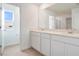 Bright bathroom with double sink vanity, white cabinets, and a view into the shower room at 216 Flag Lilly Ln, Umatilla, FL 32784
