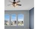 Bedroom with blue walls featuring a ceiling fan and three windows with views of the neighborhood at 2255 Stone Lake Ct, Orlando, FL 32824