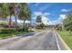 Gated community entrance with lush landscaping and palm trees lining the drive under a bright blue sky at 2255 Stone Lake Ct, Orlando, FL 32824