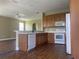 Bright kitchen with white appliances, wood cabinets, laminate flooring, and a view of the open-concept living space at 2255 Stone Lake Ct, Orlando, FL 32824