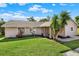 Charming single-story home with lush green lawn and mature palm trees in a sunny setting at 3 Trophy Ln, Kissimmee, FL 34759