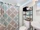 A functional bathroom features classic fixtures, a patterned shower curtain, and storage shelves at 301 Oregon Ave, St Cloud, FL 34769