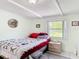 This quaint bedroom has white wood plank ceilings and a bright window looking out onto the manicured yard at 301 Oregon Ave, St Cloud, FL 34769