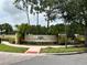 Community sign featuring stone walls, lush landscaping and palm trees at 3664 Wilshire Way Rd # 261, Orlando, FL 32829