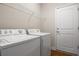 Functional laundry room with white washer and dryer, a storage rack, and a convenient access door at 3991 Island Lakes Dr, Winter Haven, FL 33881