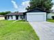 Charming single-story home featuring an attached two-car garage and a well-manicured front lawn at 406 Long Dr, Kissimmee, FL 34759