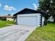 Attached two-car garage with white door and well manicured lawn at 406 Long Dr, Kissimmee, FL 34759