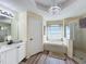 Bright main bathroom featuring a chandelier, soaking tub with window, glass shower, and white cabinets at 458 Moscato Dr, Davenport, FL 33897